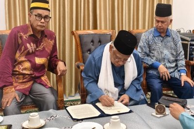 Mubarak (tengah) menandatangani pengisytiharan pemecatan Tuanku Muhriz dalam sidang media khas di Balai Undang Sungei Ujong pada Ahad lalu.