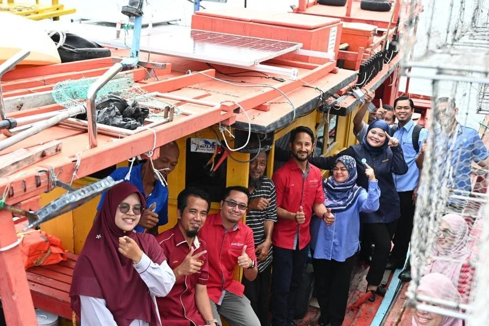 Ketua Pegawai Operasi Kumpulan dan Ketua Pegawai Kelestarian Kumpulan Bank Islam, Mohamed Iran Moriff Mohd Shariff (lima dari kiri) bergambar di atas bot nelayan yang telah dipasang panel solar fotovoltan (PV), bersama pemilik bot, Aznan A. Razak (berbaju belang), serta pegawai-pegawai daripada Bank Islam, UTM dan LKIM.