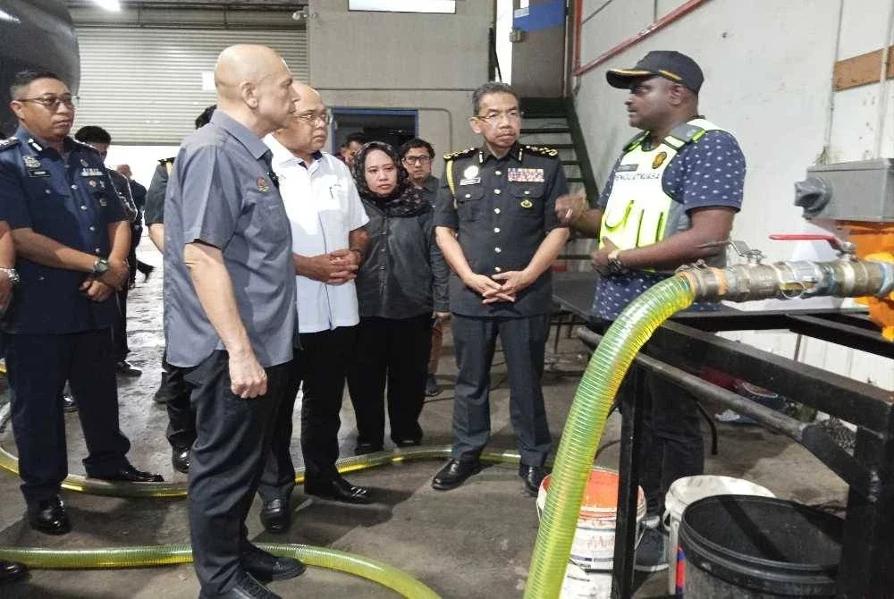 Armizan (kiri) melihat tong berisi minyak diesel yang berjaya dipatahkan oleh penguatkuasa KPDN di kawasan perindustrian Taman Mount Austin, Johor Bahru pada Khamis.