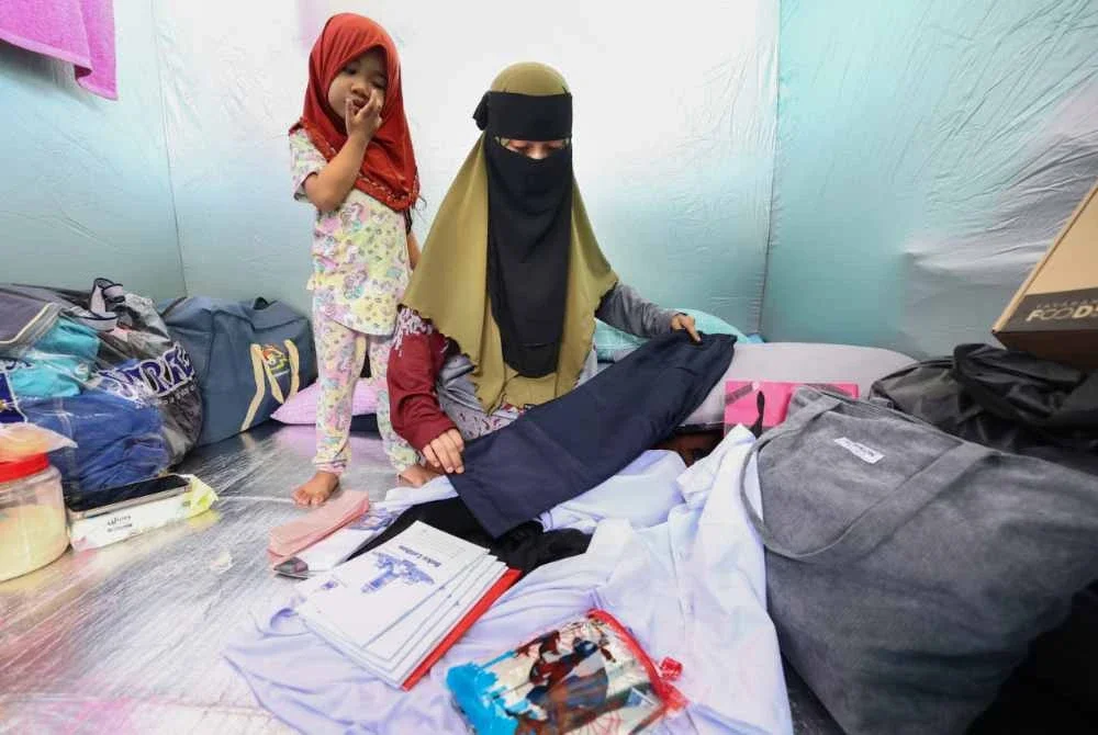 Maya melipat baju seragam sekolah anaknya yang disumbangkan oleh pihak sekolah ketika ditemui di Pusat Pemindahan Mangsa Kebakaran di Dewan Sekolah Kebangsaan Kampung Gas. Foto Bernama
