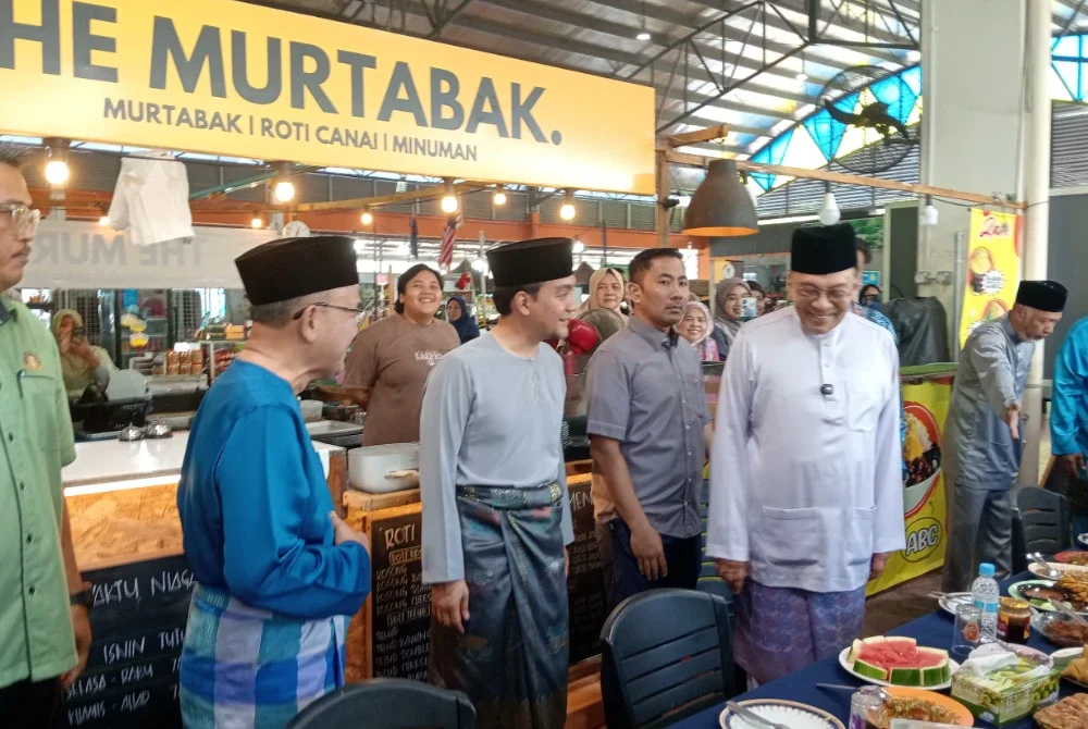 Anwar (kanan) ketika makan tengah hari di Pasar Tani Kekal Permas Jaya pada Jumaat.