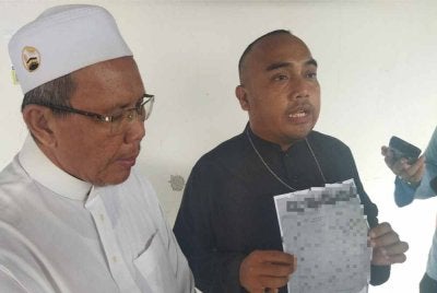 Mohd Firdaus (kanan) bersama Abdullah menunjukkan dokumen minit mesyuarat yang tular di media sosial. 