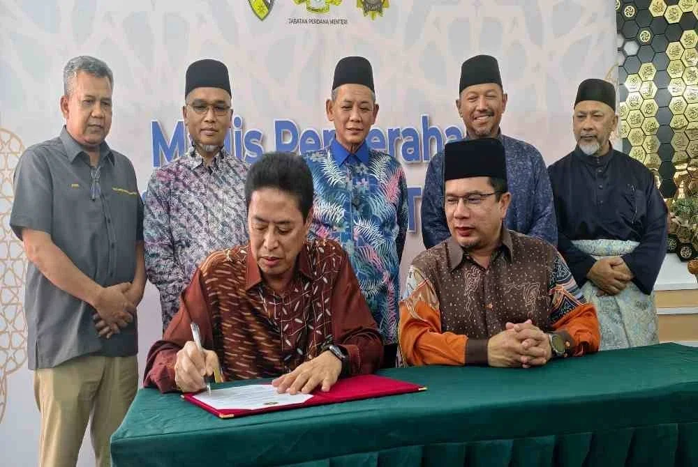 Azam menandatangani dokumen penyerahan Masjid Kariah Kampung Terentang sambil diperhatikan Mohd Asri(duduk kanan) dan Aminuddin