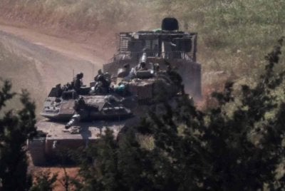Kereta kebal dan sebuah kenderaan berperisai bergerak di Lubnan, dilihat dari bahagian Israel di sempadan Israel–Lubnan, di utara Israel. Foto Reuters