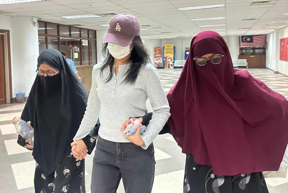 Mariah (kiri) bertudung hitam dan Farhah Sobrina yang memakai jubah dan tudung merah (kanan) dilepaskan dan dibebaskan daripada pertuduhan berkaitan ideologi keganasan oleh Mahkamah Tinggi pada Isnin.