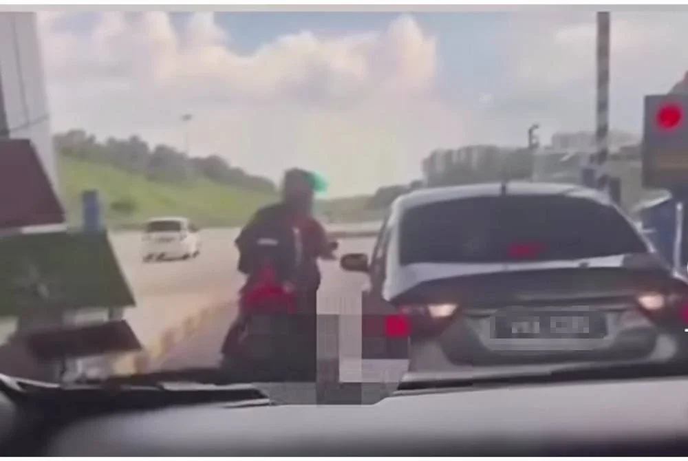 Tangkap layar video tular memaparkan seorang penunggang motosikal menendang sebuah kereta di Plaza Tol Kajang pada Ahad.