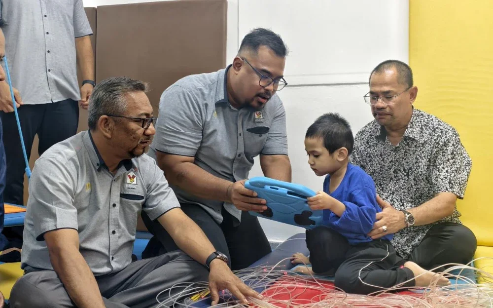 Pengurus Besar, RMHC Malaysia, Mohd Nasri Mohd Nordin (kiri) dan Ketua Pengarah Kebajikan Masyarakat, Datuk Che Murad Sayang Ramjan (kanan) menyantuni salah seorang kanak-kanak autisme di Taman Sinar Harapan Tuanku Ampuan Najihah di Seremban sempena Bulan Kesedaran Autisme.