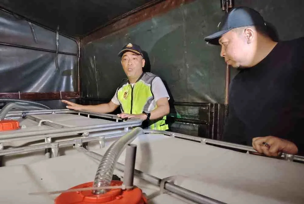 Mohd Sabri (kiri) menunjukkan tangki khas yang dimuatkan dalam lori untuk pengisian diesel, pada Rabu.