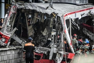 Pekerja membersihkan serpihan di lokasi perlanggaran kereta api selepas lokomotif sebuah tren penumpang merempuh dan menembusi gerabak belakang tren komuter di Stesen Bekasi Timur, Bekasi, Jawa Barat. Foto AFP