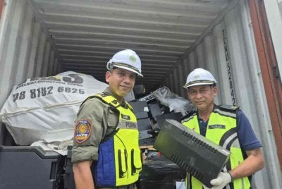 Nik Ezanee (kiri) bersama bersama kontena mengandungi pelbagai e-waste yang dikesan di Pelabuhan Klang pada Rabu.