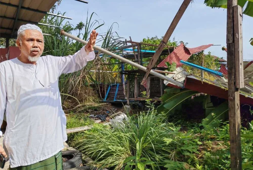 Muhamad Roslan menunjukkan garaj di rumahnya yang diterbangkan angin dalam kejadian pada petang Khamis.