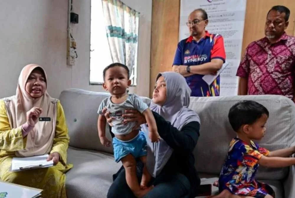 Pengarah Perkeso Terengganu Faridah Che Hussin (kiri) menyantuni Nurul Hanis Amelia Ramli sekeluarga di Kampung Peroh, Hulu Terengganu pada Khamis. Foto Bernama