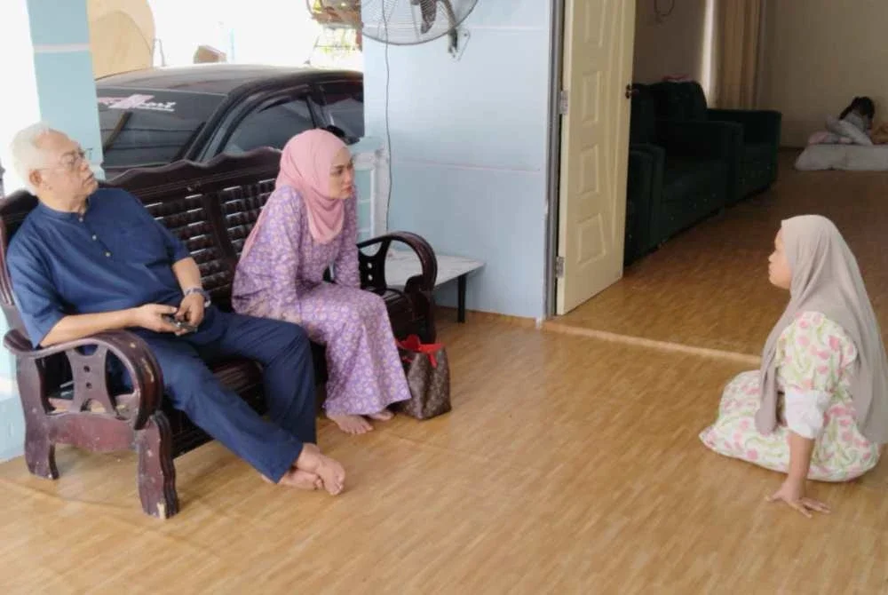 Noh dan Nurul Syazwani menziarahi Siti Nor Sayikilla (kanan) di kediamannya di Kampung Sawah Sempadan, Tanjong Karang pada Jumaat.