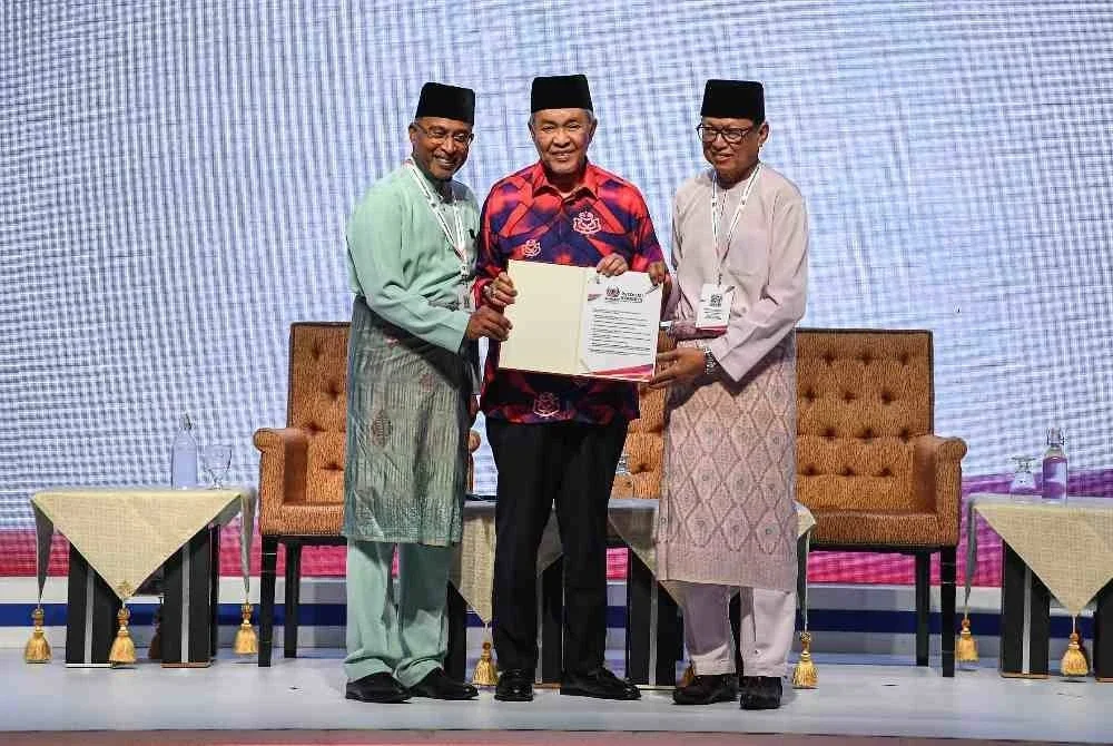 Ahmad Zahid (tengah) menerima Resolusi Kongres daripada Zambry (kiri) dan Mohd Puad pada Majlis Penutup dan Penyerahan Resolusi Kongres Pendidikan Bumiputra sempena Sambutan Ulang Tahun Umno ke-80 di Dewan Merdeka WTC Kuala Lumpur pada Jumaat.