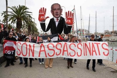Aktivis pro-Palestin mengadakan demonstrasi dengan membawa patung karikatur Perdana Menteri Israel, Benjamin Netanyahu serta sepanduk bertulis pembunuh di Barcelona. Foto AFP