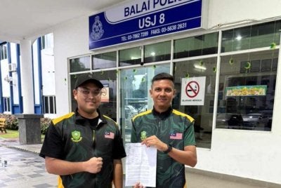 Adam Shah dan Ahmad Haziq Bin Ahmad Halimy, Setiausaha Kawasan Subang Gerakan Belia 4B (bertopi) menunjukkan laporan Polis yang dibuat di Balai Polis USJ8.