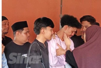 Mohd Izat (dua kanan) ditenangkan ahli keluarga ketika berada di Unit Perubatan Forensik Hospital Kota Tinggi.
