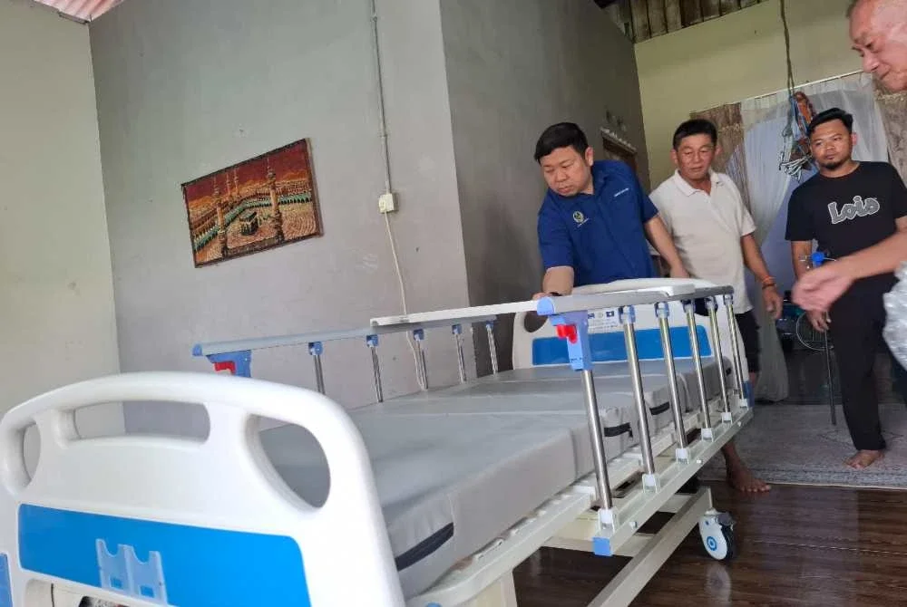 Shin Heng (kiri) memeriksa katil perubatan baharu yang siap dipasang bagi kegunaan seorang pesakit warga emas sempena Program Ziarah Kasih di Kampung Lubuk Mas, Chenderiang pada Ahad.