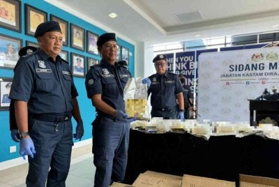 Ahmad Taufik (tengah) menunjukkan dadah yang dirampas JKDM Sabah di Pelabuhan Sepanggar, Kota Kinabalu.