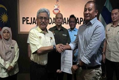 Armizan (tengah) menyaksikan penyerahan SST antara Jabatan Kerja Raya (JKR) dan kontraktor dilantik di Pejabat Daerah Papar.