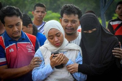 Afiqah Abdul Jalil, 33, (tengah) tidak dapat menahan kesedihan semasa memberi penghormatan terakhir kepada jenazah bapanya yang juga pelakon veteran Allahyarham Abdul Jalil Abdul Hamid, 69, pada upacara pengkebumian di Tanah Pekuburan Islam Seksyen 21 Shah Alam pada Isnin. Foto Bernama. 