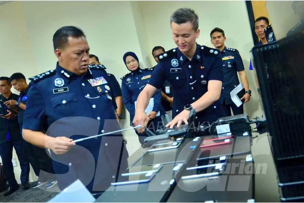 Rusdi (kiri) menunjukkan antara barang yang dirampas membabitkan sindiket love scam yang ditumpaskan pada 24 April lalu. Foto: SINAR HARIAN/ASRIL ASWANDI SHUKOR