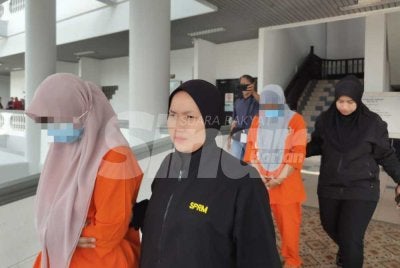 Wanita itu dibawa keluar dari Mahkamah Majistret Ayer Keroh selepas proses permohonan reman selesai. Foto Sinar Harian 