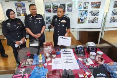 Adzli (kanan) menunjukkan barang rampasan susulan penahanan ahli Geng Atan pada sidang media di IPK Kedah pada Selasa.