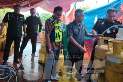 Sabri (dua dari kanan) menunjukkan tong gas subsidi berkapasiti 14kg yang dirampas dalam serbuan di stor haram di Semenyih pada Selasa.