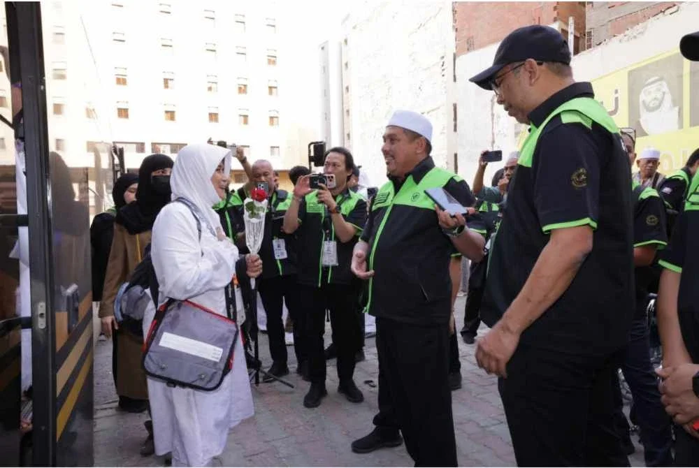 Ketua Rombongan Haji, Mohd Hisham Harun (tengah) menyambut ketibaan jemaah KT051.