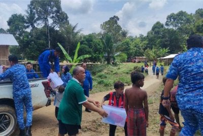 Anggota APM Lipis membantu mengagihkan sumbangan kit makanan kepada penduduk kampung terjejas banjir di Pos Sinderut pada Rabu. - Foto: APM Lipis