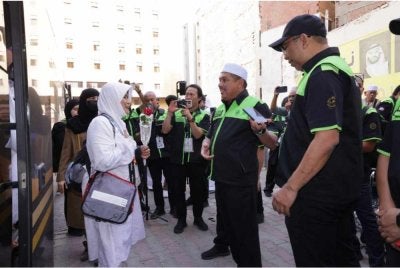 Ketua Rombongan Haji, Mohd Hisham Harun (tengah) menyambut ketibaan jemaah KT051.