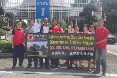 Ahmad Jufliz (tiga dari kiri) bersama ahli PRM dan penduduk memegang kain rentang di hadapan Pejabat SUK Bangunan Sultan Salahuddin Abdul Aziz Shah pada Khamis.