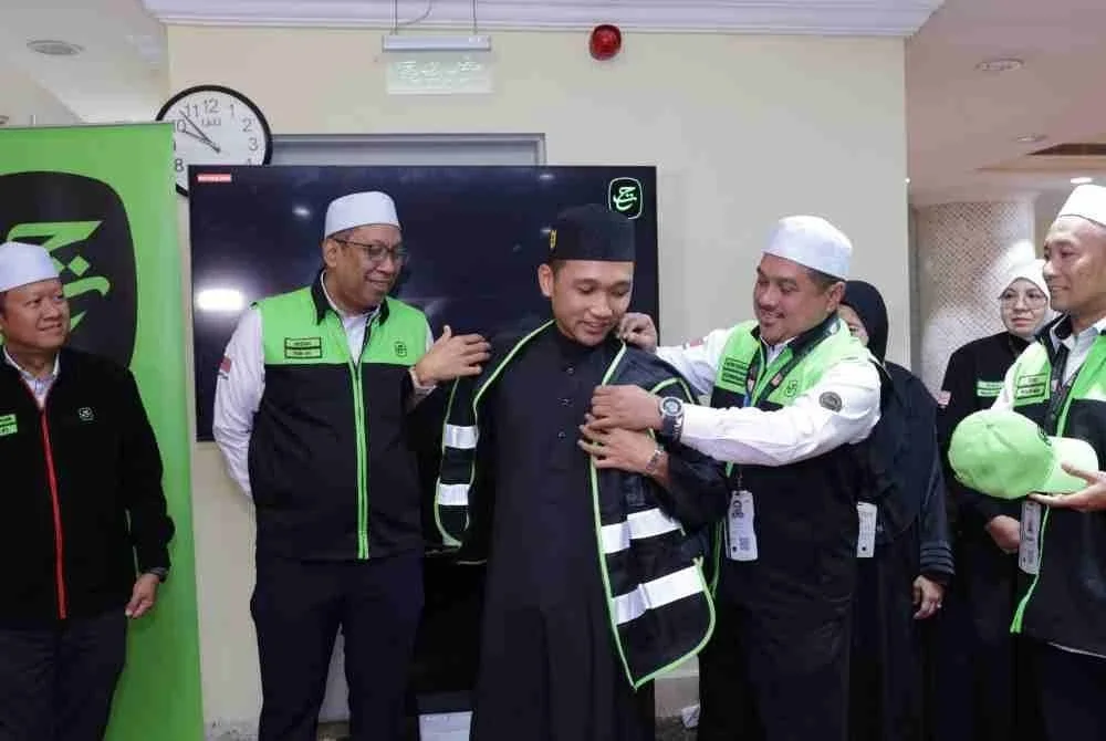 Mohd Hisham menyarungkan jaket Sahabat Maktab kepada sukarelawan.