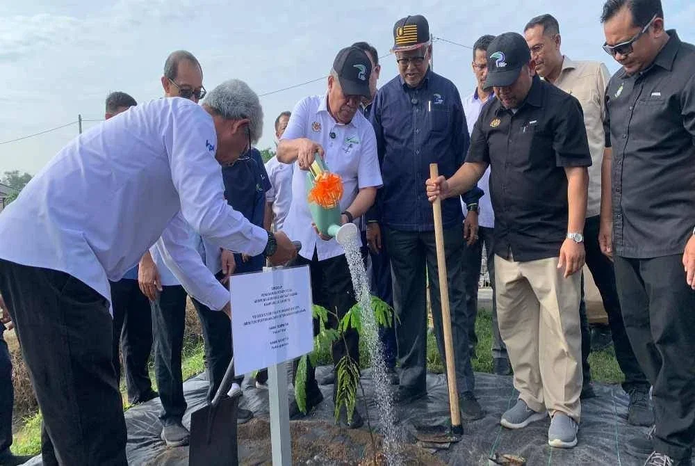 Mohamad (tengah) menanam pokok petai sebagai simbolik ketika merasmikan Program Kampung Angkat Madani, Kampung Guar Petai di Tasek Gelugor pada Jumaat.