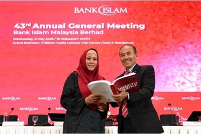Teh Maimunah (kiri) bersama Ismail melihat Laporan Tahunan Bersepadu Kumpulan 2025 yang bertemakan 'Resilient Stronger' pada Mesyuarat Agung Tahunan Bank Islam ke-43 yang diadakan di Kuala Lumpur.