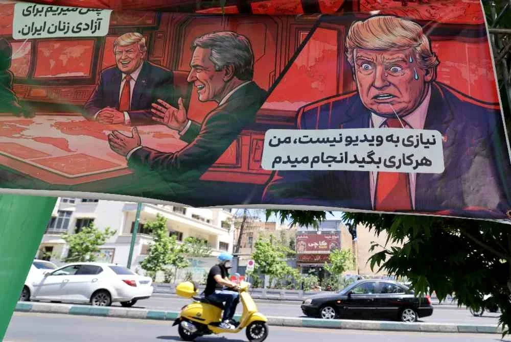 Seorang lelaki Iran menunggang motosikal kecil melintasi sepanduk yang memaparkan karikatur Presiden Amerika Syarikat, Donald Trump di Teheran. Foto: AFP