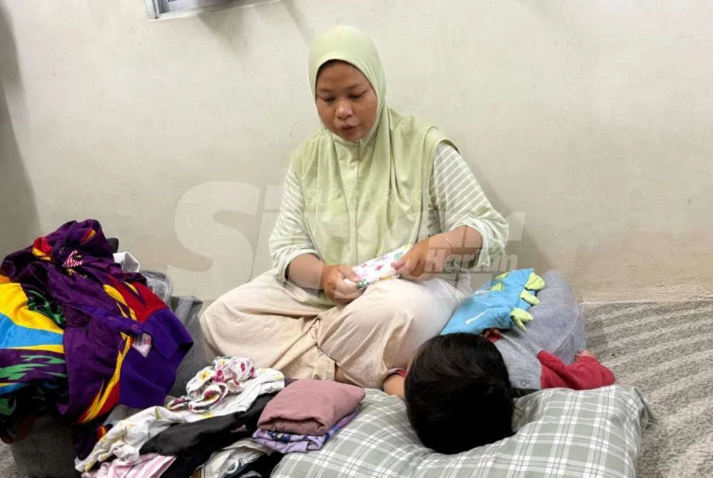 Nur Asyikin mengambil upah melipat baju bagi tambah pendapatan sara dua anak. Foto Sinar Harian