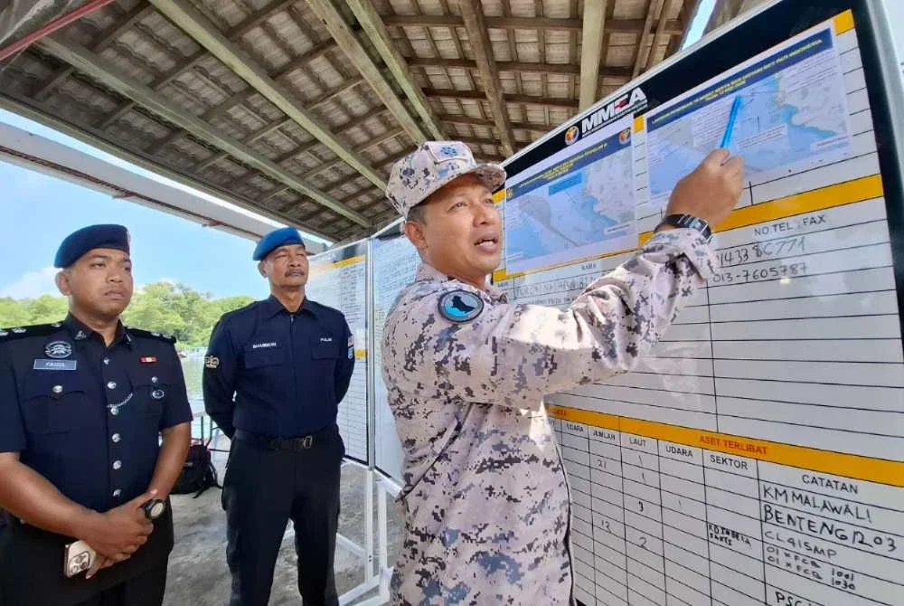 Mohamad Shukri (kanan) menunjukkan peta lokasi penemuan tujuh mayat mangsa pada hari kedua operasi.