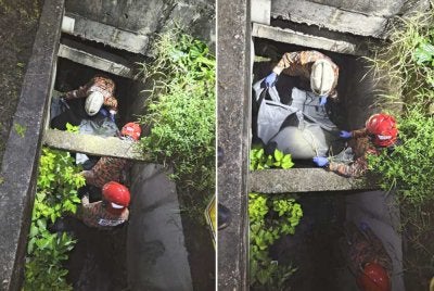 Anggota bomba mengeluarkan mangsa dari dalam longkang.
