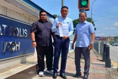 Shafiq (tengah) menunjukkan salinan laporan polis yang dibuat terhadap Nik Muhammad Zawawi berhampiran pintu masuk IPD Ipoh pada Rabu.