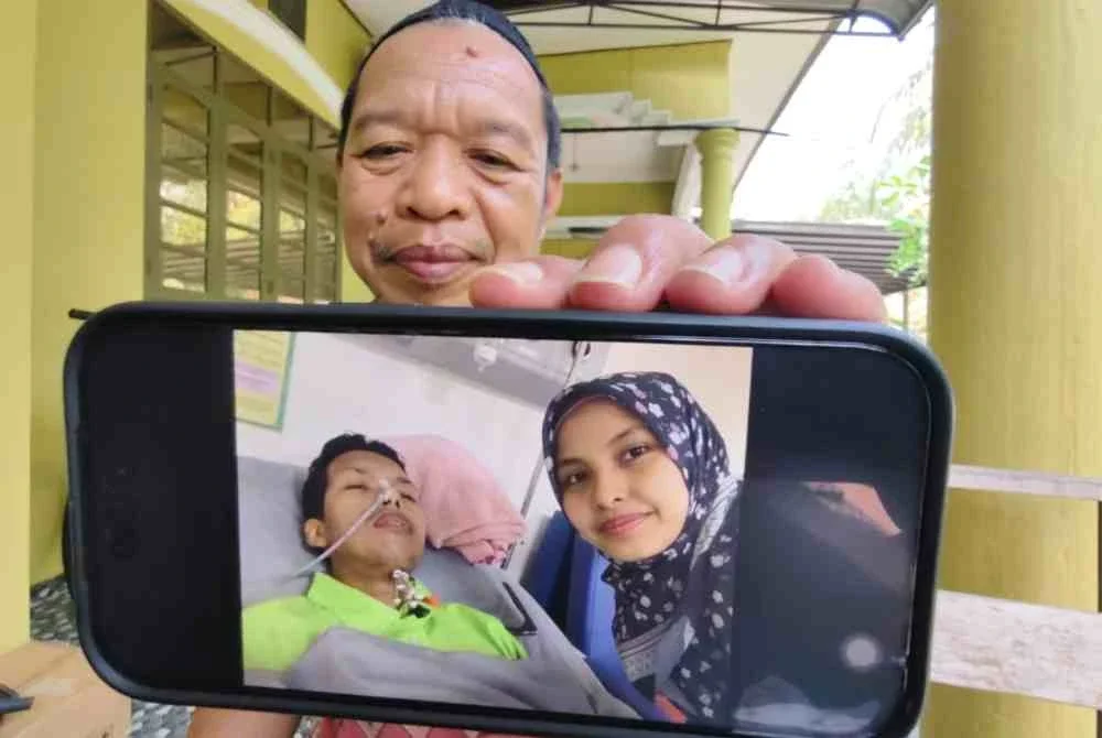 Mahadi menunjukkan gambar anaknya, Mohd Arif ditemani isteri, Rahimah yang kini dirawat di Pusat Perubatan Universiti Sains Malaysia (USM) Bertam, Pulau Pinang.