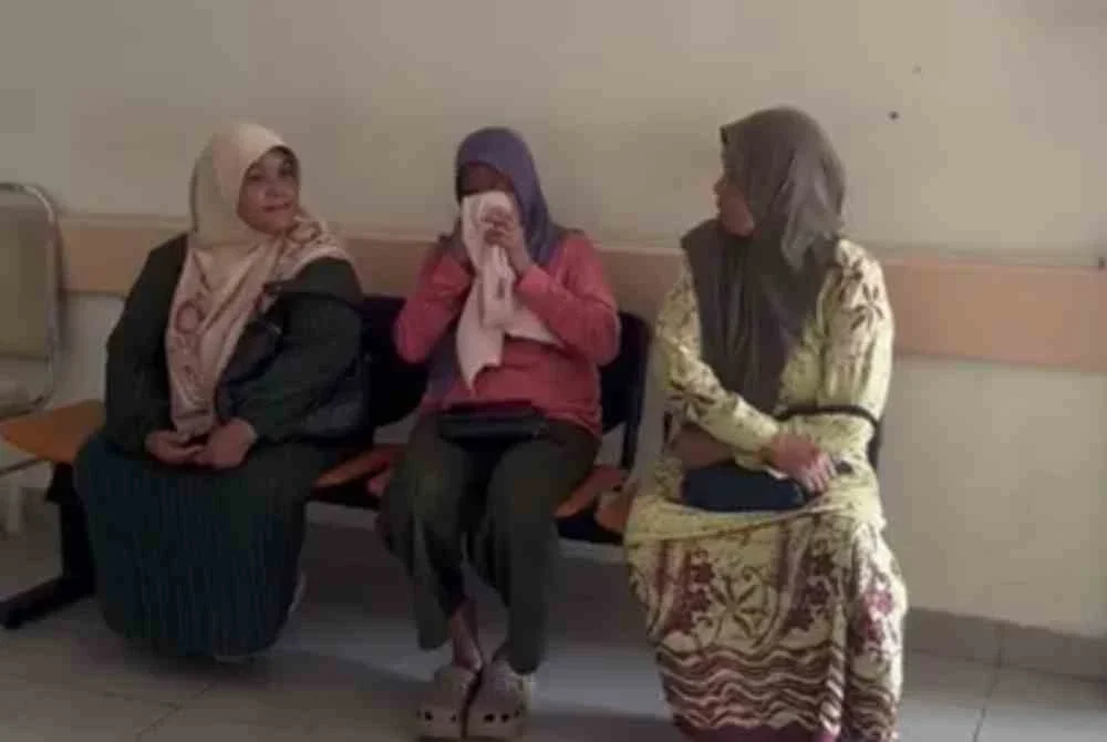 Ropiah (tengah) yang mengelap air mata semasa berada di Jabatan Forensik Perubatan Hospital Gua Musang.