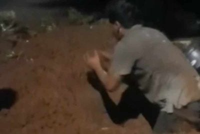 Agus terus menggali kubur ibunya meskipun lampu telah dipadamkan di tanah perkuburan berkenaan. Foto Agensi
