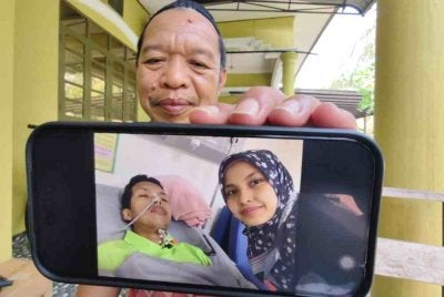 Mahadi menunjukkan gambar anaknya, Mohd Arif ditemani isteri, Rahimah yang kini dirawat di Pusat Perubatan Universiti Sains Malaysia (USM) Bertam, Pulau Pinang.