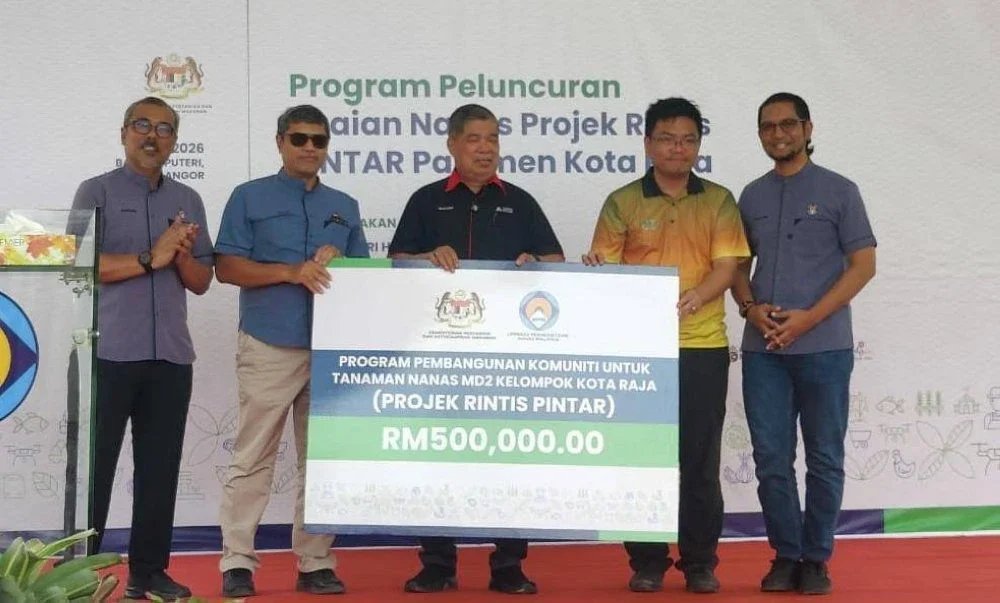 Mohamad (tengah) menyerahkan replika cek kepada salah seorang penerima pada Program Peluncuran Tuaian Nanas di Projek Rintis Pintar Parlimen Kota Raja.