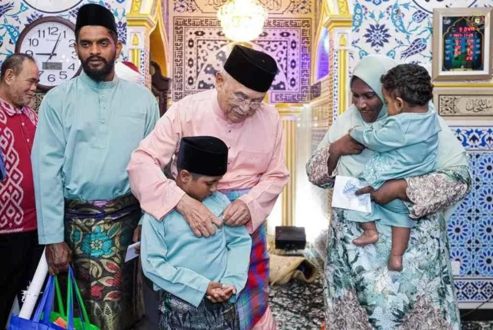 Tun Mohd Ali (dua dari kiri) beramah mesra dengan keluarga yang baharu memeluk Islam. Foto: Istana Melaka.