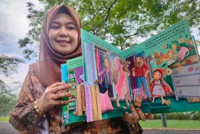 Suraya menunjukkan buku kesayangannya yang digunakan sebagai pencerita.