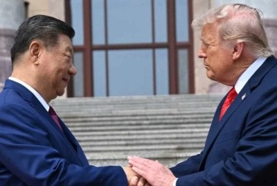 Presiden China Xi Jinping berjabat tangan dengan Presiden Amerika Syarikat Donald Trump di Great Hall of the People, Beijing. - Foto AP