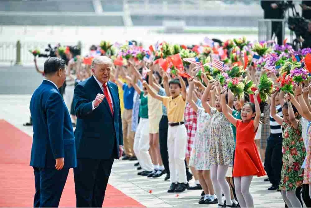 Trump (kanan) dan Jinping (kiri) menyapa kanak-kanak yang mengibarkan bendera kebangsaan China dan Amerika Syarikat serta bunga semasa upacara sambutan rasmi di Dewan Besar Rakyat di Beijing.